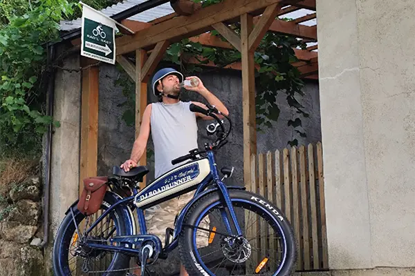 Rdfahrer mit stylischem E-Bike macht Pause und trinkt ein Erfrischungsgetränk